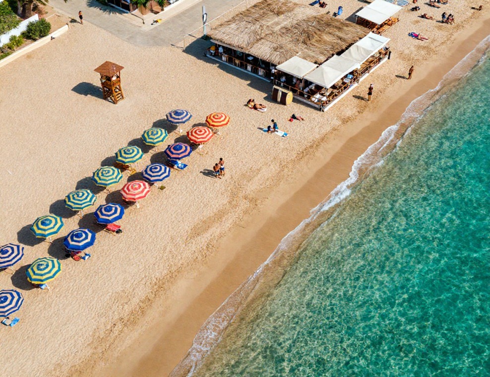 Vista aerea di stabilimento balneare con ombrelloni colorati e mare cristallino